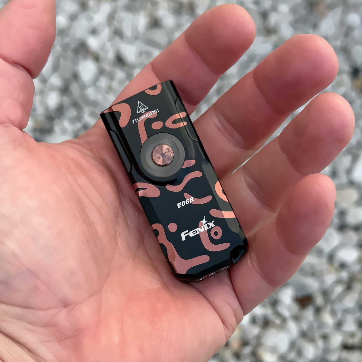 Fenix E06R – Schlüsselbundlampe mit 700 Lumen, UV-Licht und rotem Laser. Graffiti-Ausführung im Größenvergleich in der Hand.