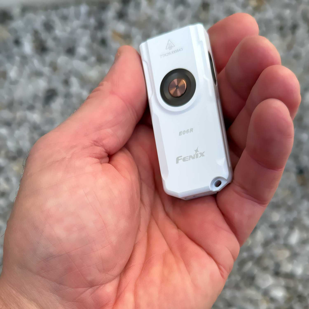 Fenix E06R – Schlüsselbundlampe mit 700 Lumen, UV-Licht und rotem Laser. Darstellung der Abmessungen der weißen Leuchte im Vergleich zur Hand.